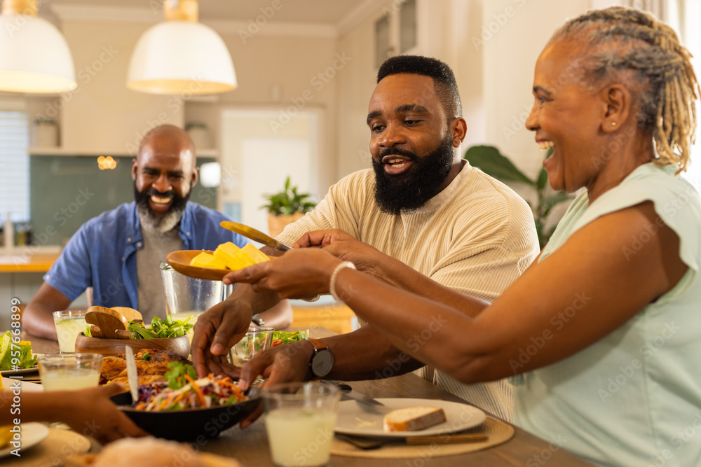 multigenerational family enjoying dinner together, sharing food and laughing around dining table multigenerational family enjoying dinner together, sharing food and laughing around dining table