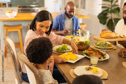 Photography multigenerational family enjoying dinner together, serving corn and salad at hom