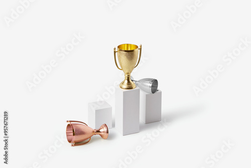 Winner gold cup standing on stand while silver and bronze lying near
