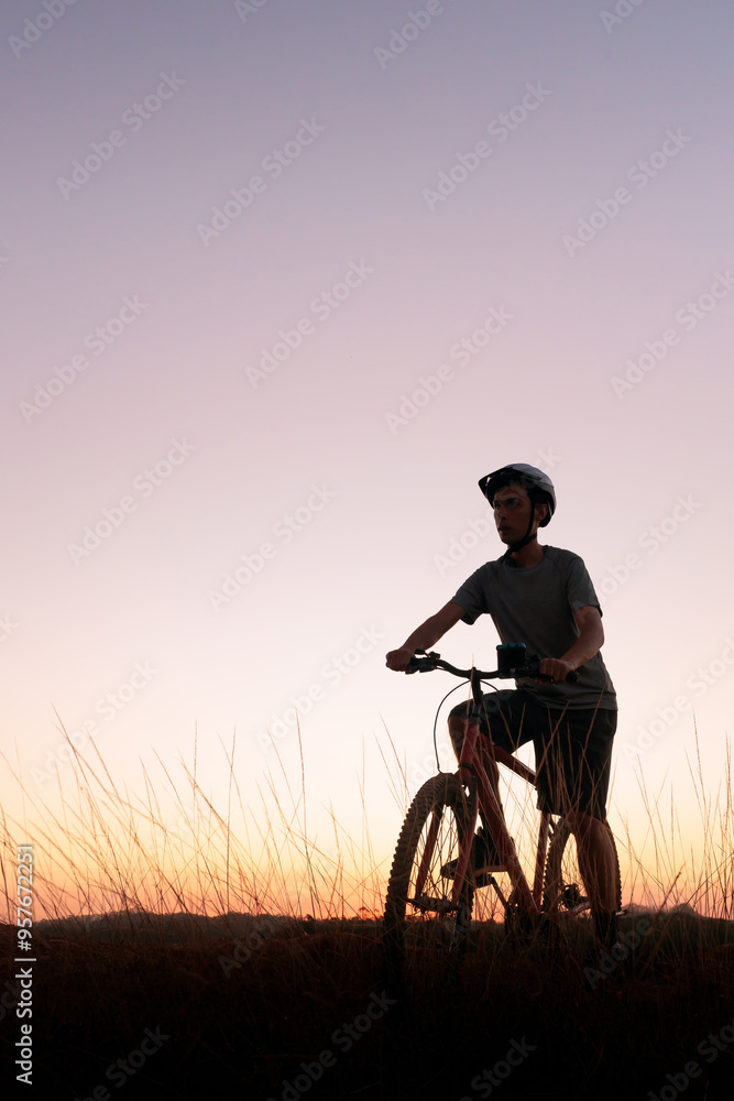 Mountain biker takes a break at dusk. The scenic sunset and peaceful atmosphere capture a sense of accomplishment and a passion for outdoor adventure. Mountain biker takes a break at dusk. The scenic sunset and peaceful atmosphere capture a sense of accomplishment and a passion for outdoor adventure.