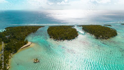 Aerial view captured by drone of tropical island Taha'a in French Polynesia. The popular tourist destination is surrounded by azure blue ocean water and covered in lush palm trees.  photo