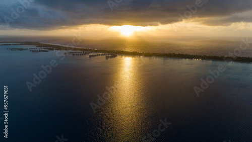 Wallpaper Mural Aerial view captured by drone overlooking tropical island resorts with overwater bungalows on Bora Bora motu in French Polynesia. Azure and turquoise colored ocean sea water. Low clouds above sunrise. Torontodigital.ca