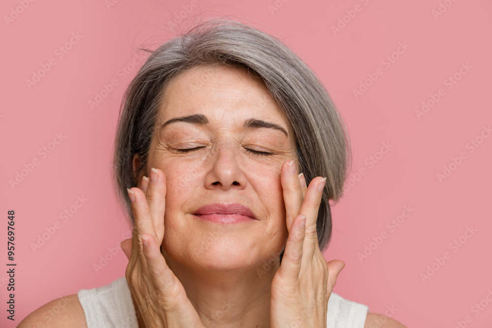 Senior woman touching face with closed eyes Senior woman touching face with closed eyes
