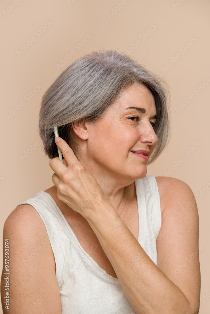 senior woman combing her gray hair senior woman combing her gray hair