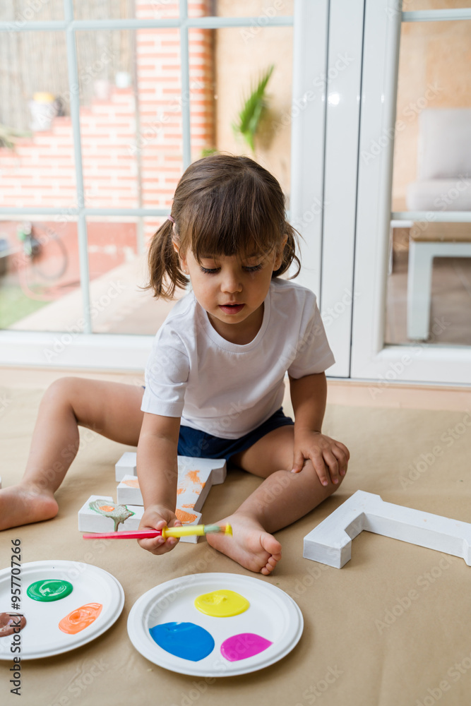 girl painting wooden letters at home on the floor girl painting wooden letters at home on the floor