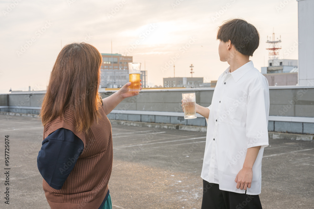 お酒と夕日を眺める男女 お酒と夕日を眺める男女