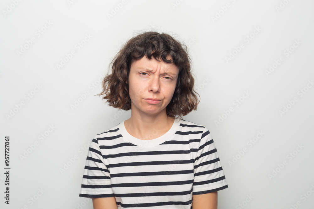 Curly-haired woman with striped shirt and slight frown. Curly-haired woman with striped shirt and slight frown.