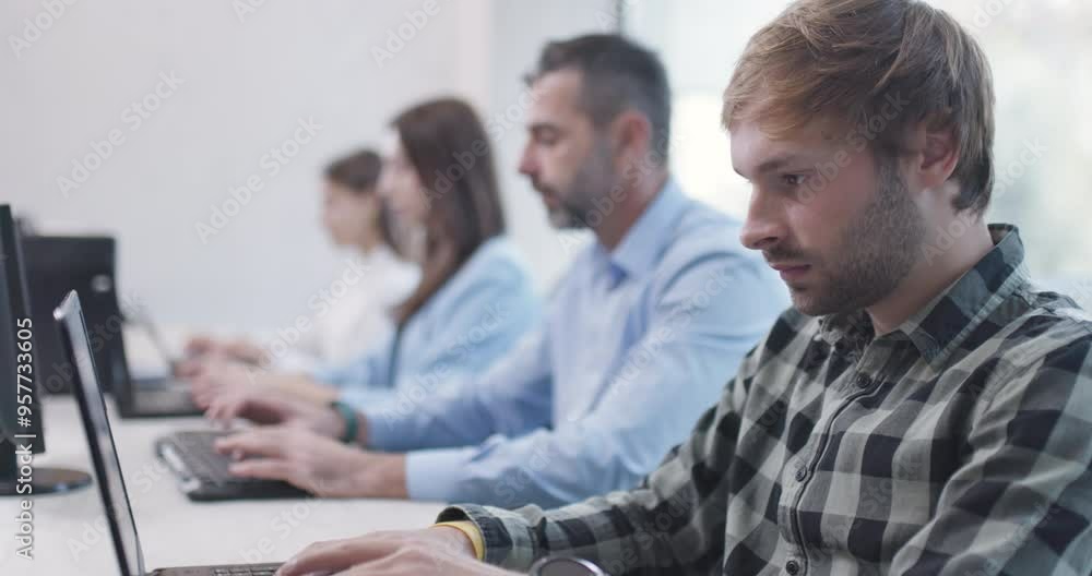 People sitting in a row in office working on computers. Bussiness colleagues team. Shallow depth of field recorded at 50fps. People sitting in a row in office working on computers. Bussiness colleagues team. Shallow depth of field recorded at 50fps.