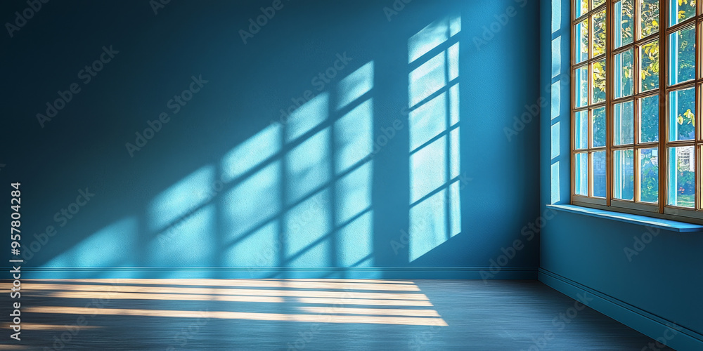 Fototapeta premium Sunlight streams through a window, casting long shadows on a blue wall and hardwood floor.