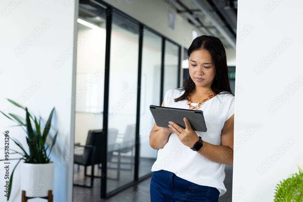 Using tablet, woman standing in modern office, focusing on work tasks, copy space Using tablet, woman standing in modern office, focusing on work tasks, copy space