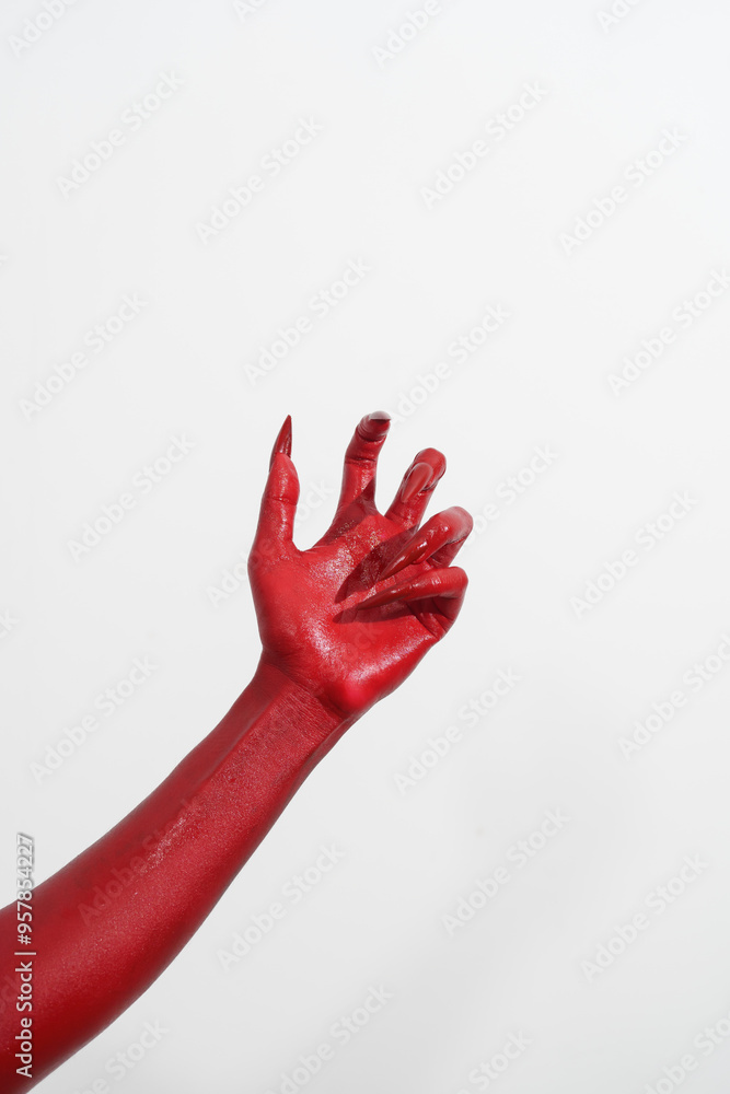 A witch's hand with long red nails on a white background, resembling a demon's or zombie's hand. This scary monster is perfect for Halloween, symbolizing a resurrected fictional creature. A witch's hand with long red nails on a white background, resembling a demon's or zombie's hand. This scary monster is perfect for Halloween, symbolizing a resurrected fictional creature.