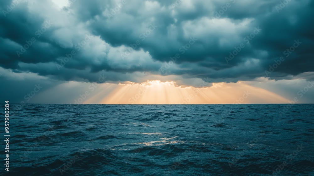 A dramatic seascape showing dark clouds parting to reveal radiant sunlight on the ocean waves, creating a serene and mystical atmosphere. A dramatic seascape showing dark clouds parting to reveal radiant sunlight on the ocean waves, creating a serene and mystical atmosphere.