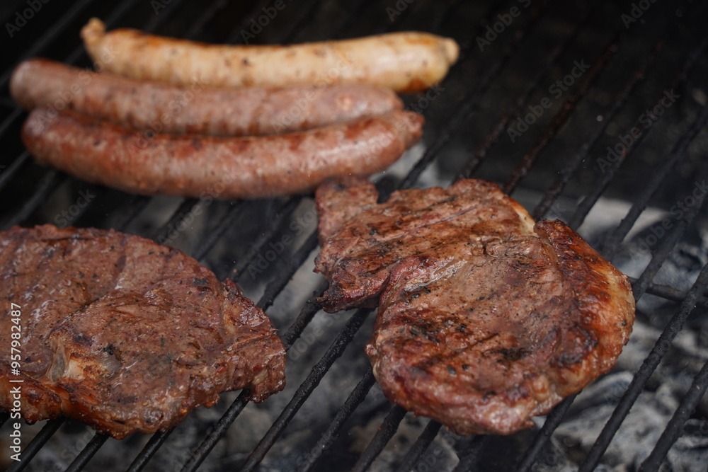 Sausages and pieces of meat are fried on the surface of the grill. Sausages and pieces of meat are fried on the surface of the grill.