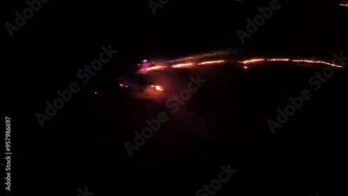 Raging fire at the dry grass meadow. Agricultural field fire burning. Night aerial footage of smoke and flame. Firefighters emergency response. Ecological catastrophe and environmental hazard. photo