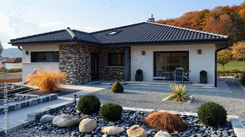 Modern single-story house with stone accents and landscaped garden in autumn foliage during daylight photo