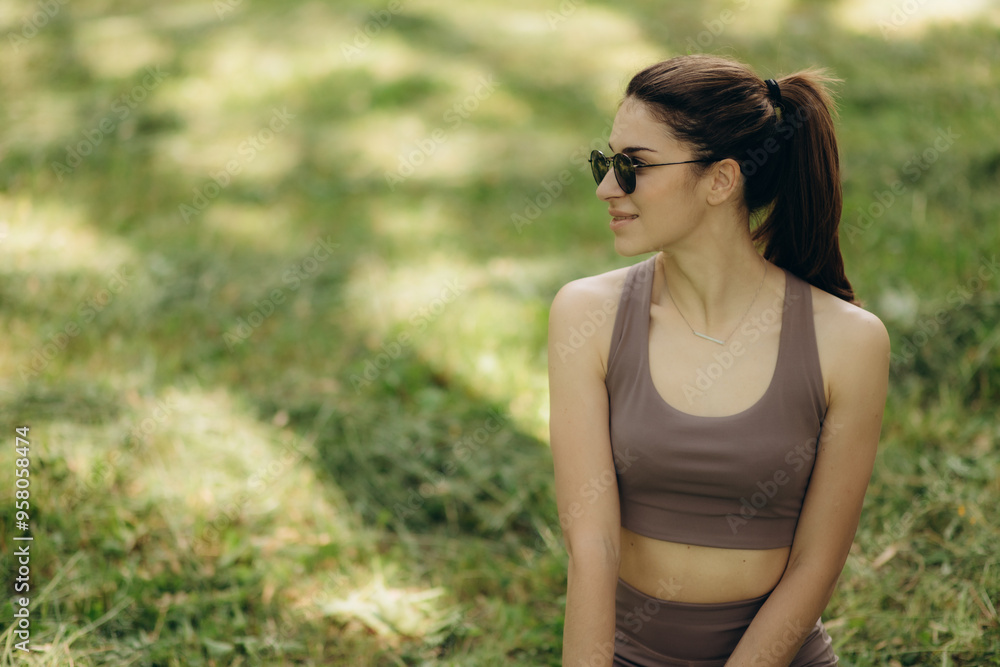 Woman in a side stretch, practicing yoga in a sunny park, dressed in teal sportswear. Girl at Outdoor exercise