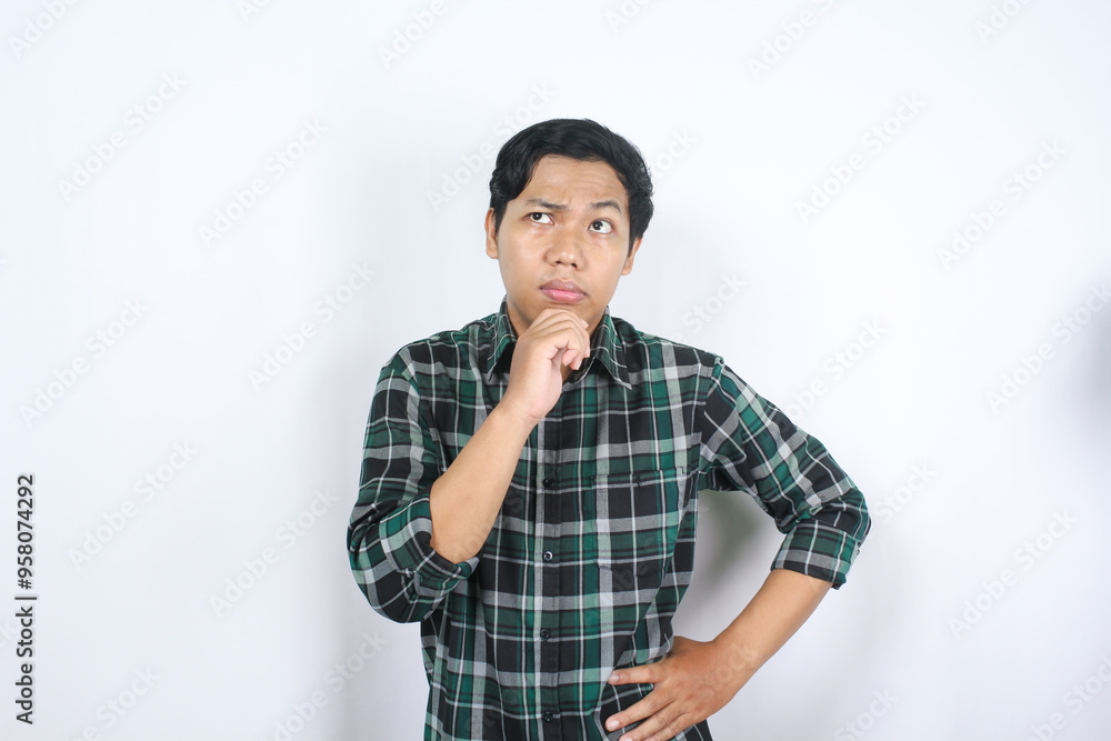 thoughtful indonesian young man looks confused standing over isolated white background wearing casual checkered shirt thoughtful indonesian young man looks confused standing over isolated white background wearing casual checkered shirt