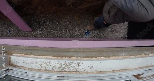 Construction worker installing rigid foam insulation on foundation wall of residential house - close up from above