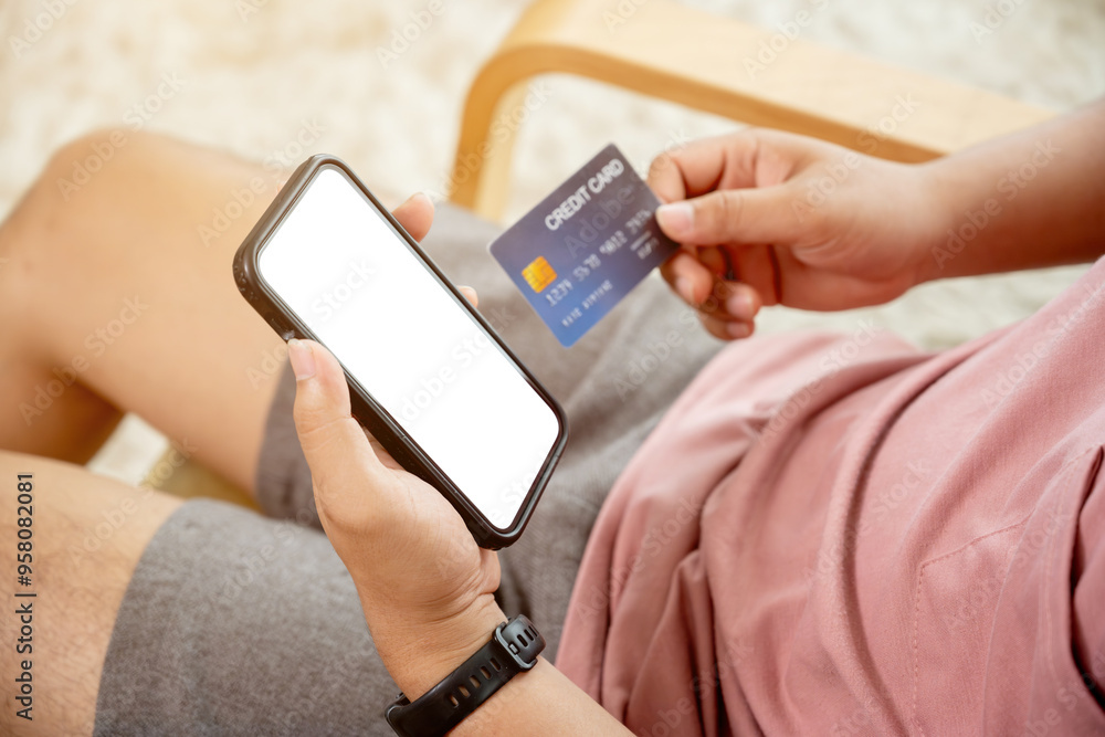 Asian man in casual clothes shopping on smartphone sitting on sofa in living room Asian man in casual clothes shopping on smartphone sitting on sofa in living room