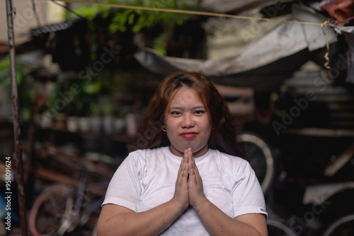 A young Filipino woman pleading for financial assistance, asking for a a favor. Slum area background. photo