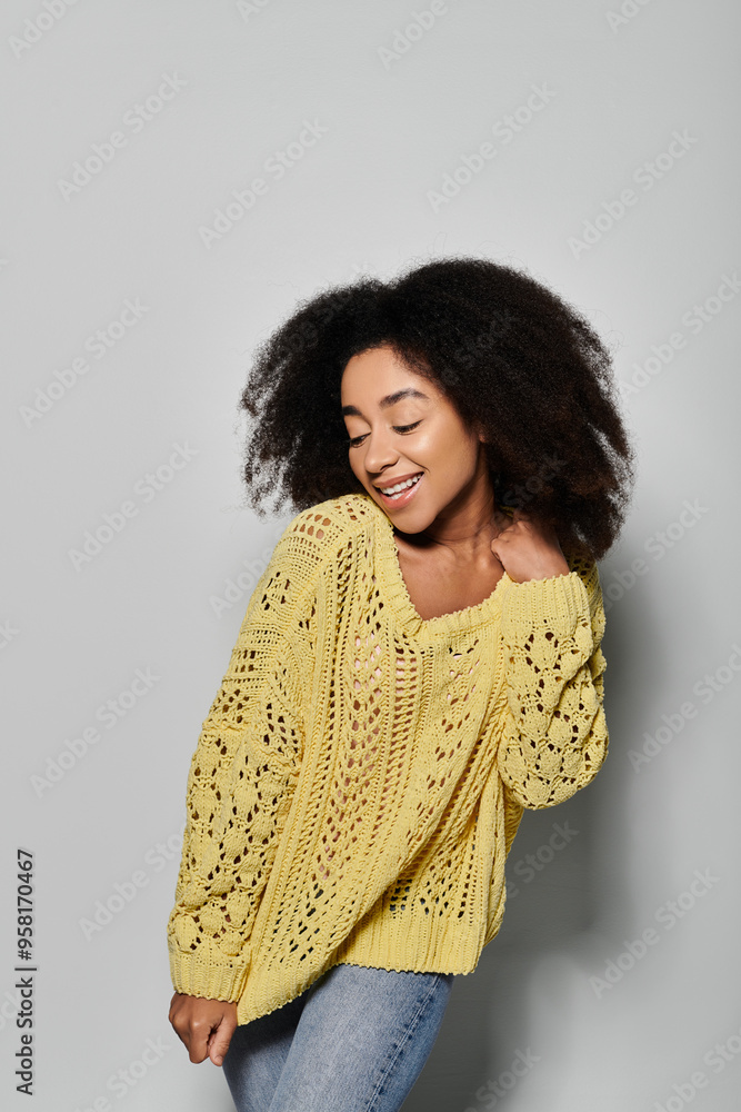 A young African American woman beams with joy, wearing a cozy yellow sweater in a studio setting. A young African American woman beams with joy, wearing a cozy yellow sweater in a studio setting.