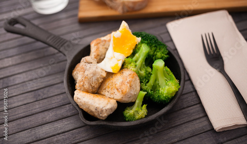 Chicken breast with broccoli and poached egg in small cast iron skillet