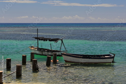 Artisanal, small, old wood fishing boats moored to wooden stakes driven into the ground of the lagoon formed by the coral reef in front of Cabo Cruz village, in the Granma Landing Park. Niquero-Cuba. photo