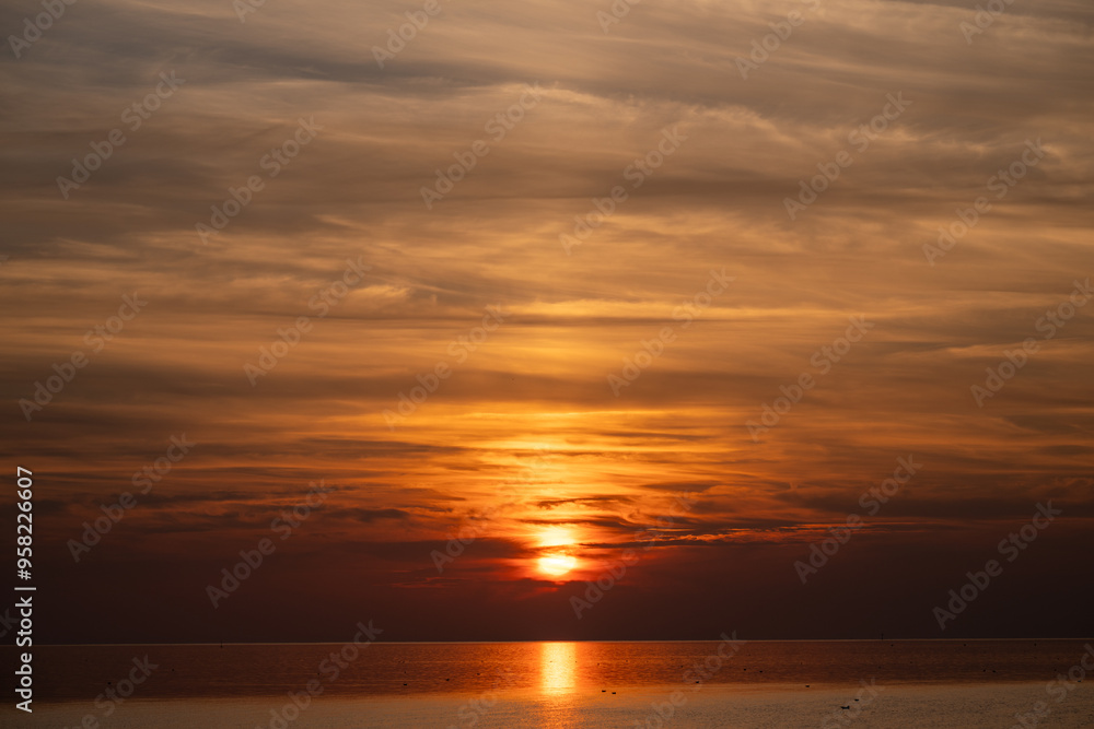 Fototapeta premium Die Nordsee bei Büsum - dramatisch schöner Sonnenuntergang mit Spiegelung auf dem Wasser und dem Watt