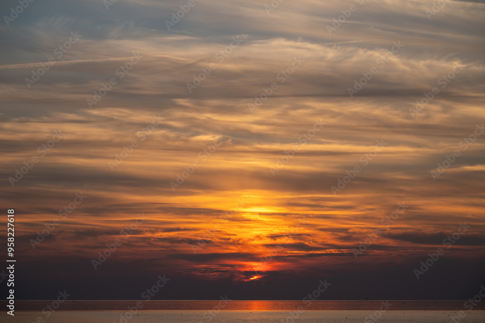 Fototapeta premium Die Nordsee bei Büsum - dramatisch schöner Sonnenuntergang mit Spiegelung auf dem Wasser und dem Watt