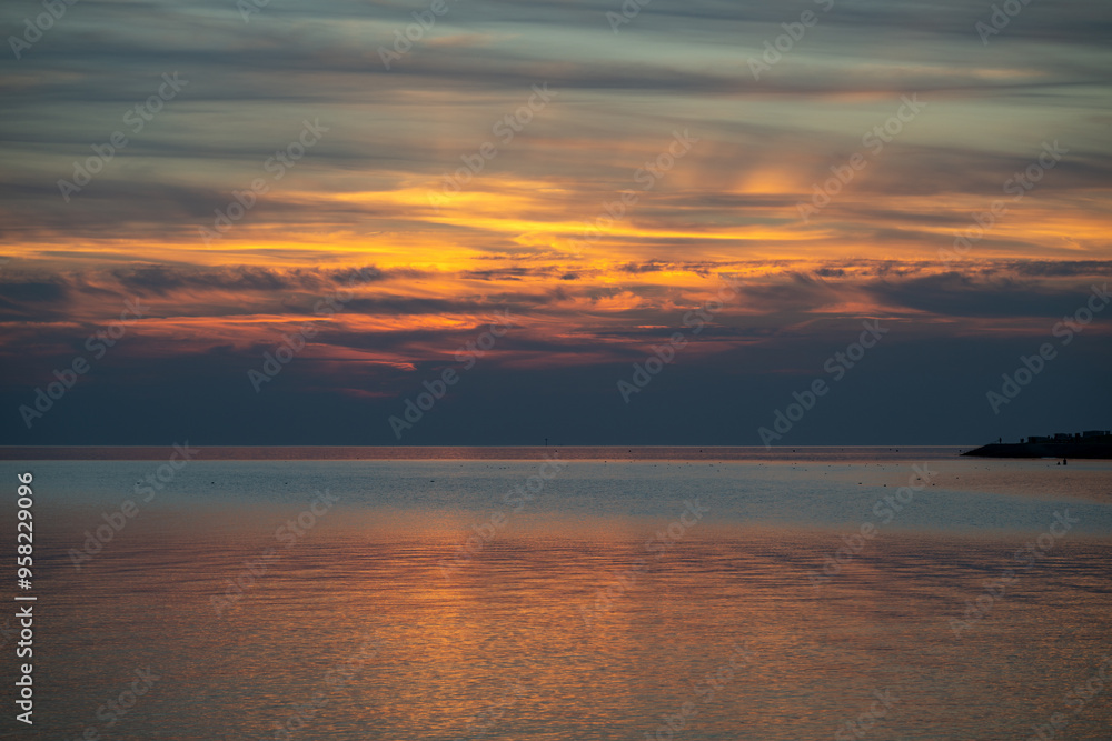 Fototapeta premium Die Nordsee bei Büsum - dramatisch schöner Sonnenuntergang mit Spiegelung auf dem Wasser und dem Watt