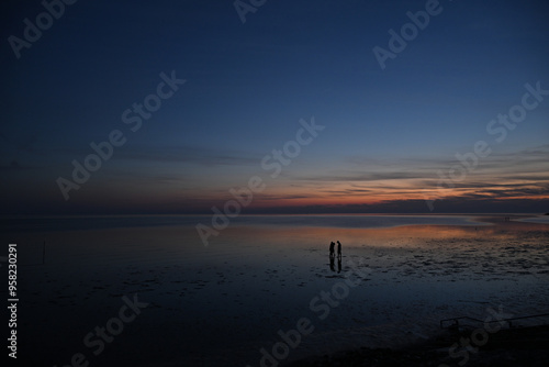 Die Nordsee bei Büsum - dramatisch schöner Sonnenuntergang mit Spiegelung auf dem Wasser und dem Watt photo