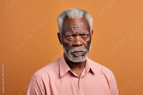 Peach background sad black American independent powerful man. Portrait of older mid-aged person beautiful bad mood expression photo