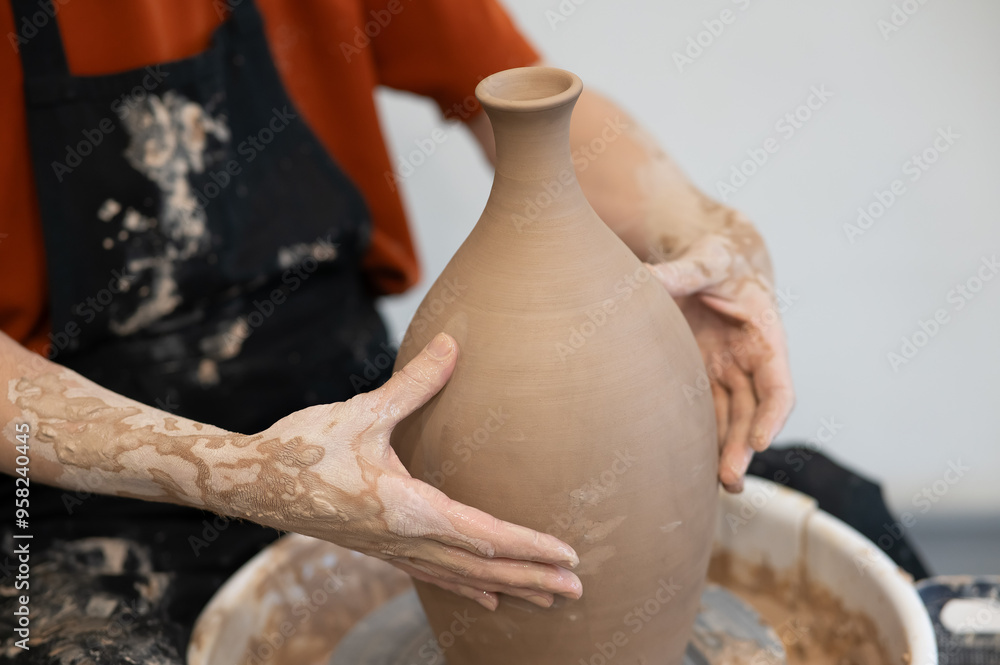 Close-up of a potter's hands making a ceramic vase on a potter's wheel. Close-up of a potter's hands making a ceramic vase on a potter's wheel.