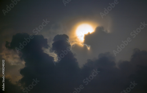 Sun disk behind dark clouds at sunset