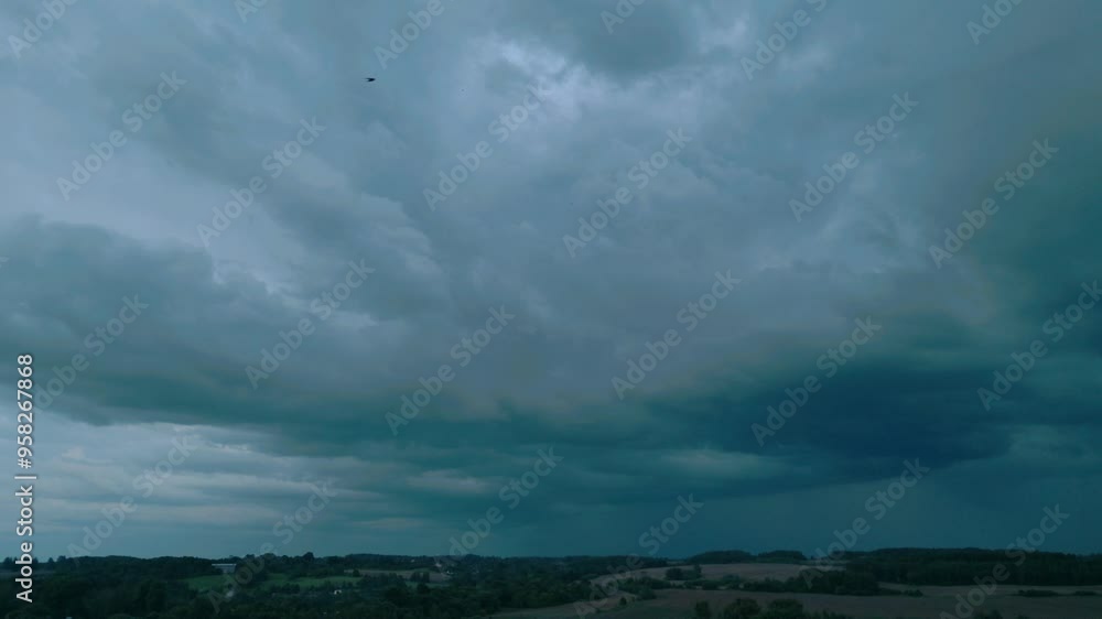 Aerial view of ominous, dark clouds gathering over a Baltic landscape, capturing the intense and dramatic atmosphere before a storm. Shot in a rural Baltic region, showing nature's raw power Aerial view of ominous, dark clouds gathering over a Baltic landscape, capturing the intense and dramatic atmosphere before a storm. Shot in a rural Baltic region, showing nature's raw power