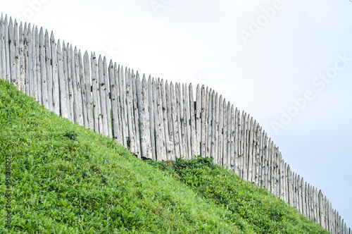 Aged wooden fence, Castle defensive wall on high green hill, vintage heritage architecture