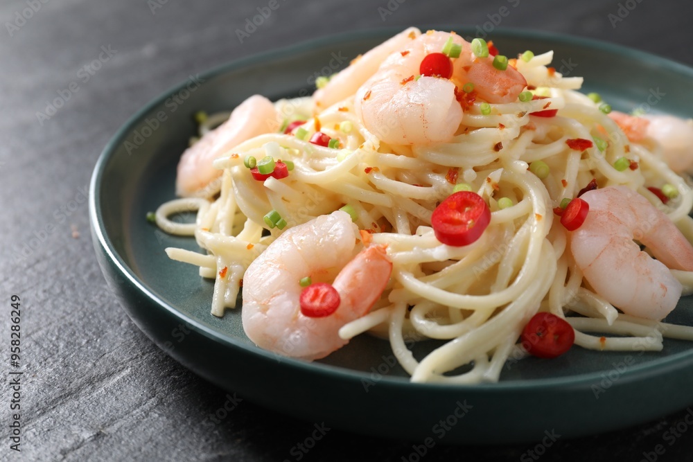 Delicious pasta with shrimps, green onion and chili pepper on black table, closeup Delicious pasta with shrimps, green onion and chili pepper on black table, closeup