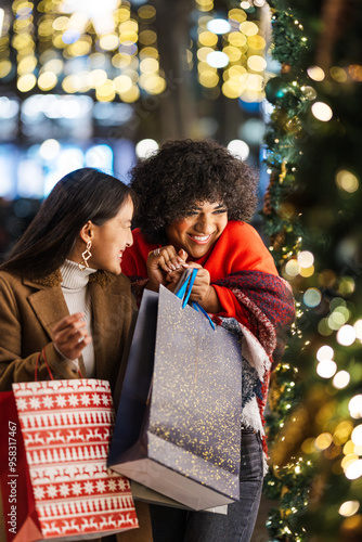 Two happy young women enjoying christmas shopping in the city at night