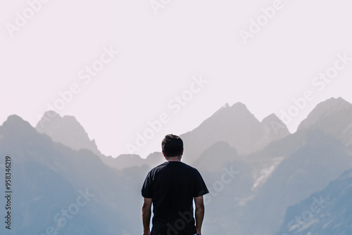 mężczyzna na tle gór patrzy na szczyty, Tatry Wysokie, grań Tatr w tym Rysy, turysta na Rusinowej Polanie