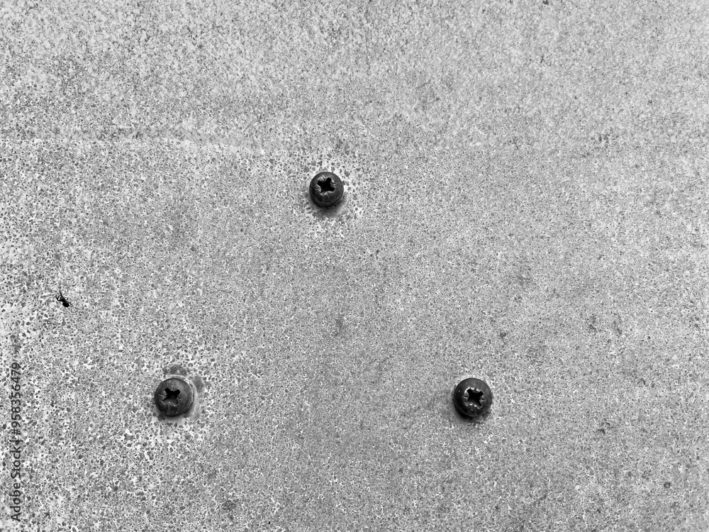 three screws arranged in a triangle in a light gray wall three screws arranged in a triangle in a light gray wall