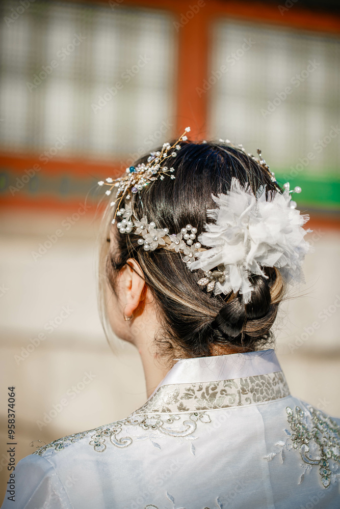 Picture of traditional Korean hairstyle for festive occasions. A girl dressed in a classic ethnic dress standing outdoor, view from the back.
