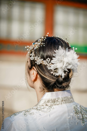 Obraz na płótnie Picture of traditional Korean hairstyle for festive occasions. A girl dressed in a classic ethnic dress standing outdoor, view from the back. w salonie