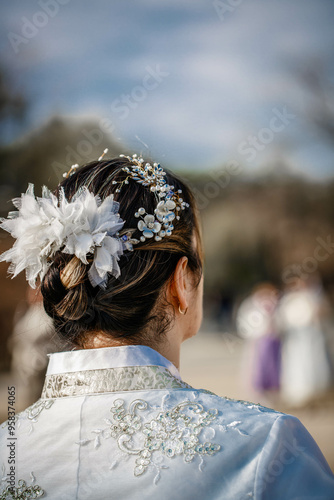 Obraz na płótnie Picture of traditional Korean hairstyle for festive occasions. A girl dressed in a classic ethnic dress standing outdoor, view from the back. w salonie