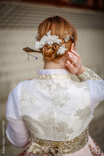 Obraz na płótnie Picture of traditional Korean hairstyle for festive occasions. A girl dressed in a classic ethnic dress standing outdoor, view from the back. w salonie