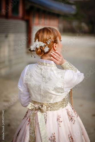 Obraz na płótnie Picture of traditional Korean hairstyle for festive occasions. A girl dressed in a classic ethnic dress standing outdoor, view from the back. w salonie