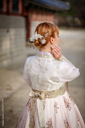 Obraz na płótnie Picture of traditional Korean hairstyle for festive occasions. A girl dressed in a classic ethnic dress standing outdoor, view from the back. w salonie