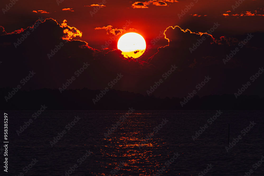 Obraz premium The Fiery Sun Sets as Red Sky Fades to Black