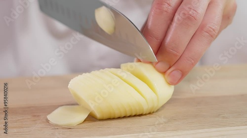 Macro. Girl cuts potatoes into thin slices with a sharp knife, on a wooden board. Boiled potatoes, potato dishes. Front view, close-up
