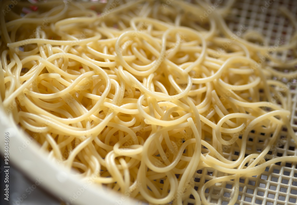 Draining pasta noodles in a plastic colander strainer Draining pasta noodles in a plastic colander strainer