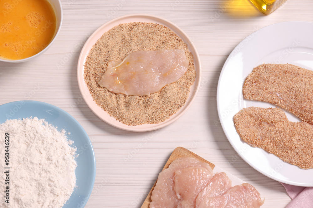 Making schnitzel. Slices of meat with bread crumbs and ingredients on white wooden table, flat lay Making schnitzel. Slices of meat with bread crumbs and ingredients on white wooden table, flat lay